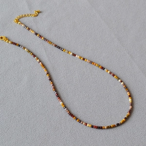 Macro detail of colorful square natural stone beads and gold adjustable clasp necklace