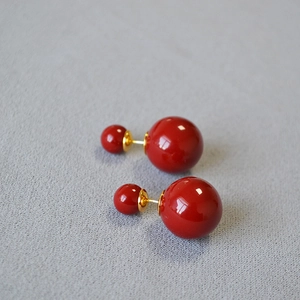 Macro view of French vintage style double pearl earrings in glossy festive wine red