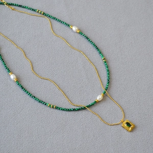 Close-up of double-layered necklace with malachite beads, pearls and emerald square pendant