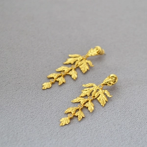 Detailed view of gold leaf earrings with textured finish and zircon accents