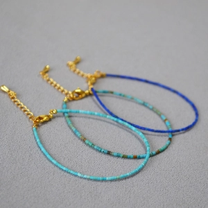 Detailed macro of three blue beaded necklaces with gold lobster clasps and extension chains