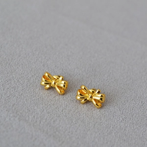 Elegant 18K gold plated bow stud earrings on a grey velvet surface, minimalist fashion jewelry