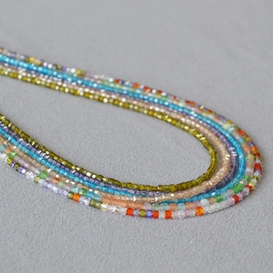 Macro view of colorful square faceted crystal beads on a layered necklace strand