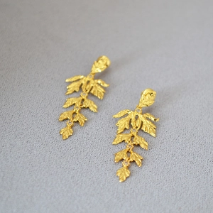 Detailed view of layered gold leaf earrings with textured finish and cubic zirconia accents