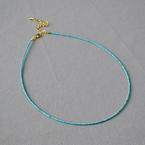 Collier turquoise rétro français avec fermoir doré sur fond de tissu gris texturé