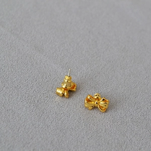 Macro shot of elegant gold bow stud earrings featuring polished finish and secure butterfly backs