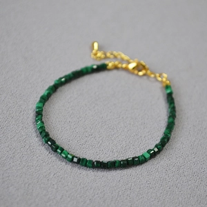 Dettaglio macro del bracciale con cubi di malachite verde e chiusura a catena dorata
