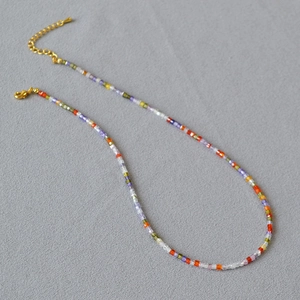 Macro detail of multi-color beaded necklace with golden lobster clasp and adjustable chain
