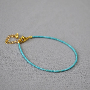 Detail of slim turquoise beaded bracelet with gold lobster clasp and extension chain