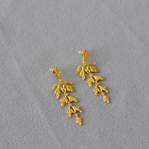Detailed view of layered leaf-shaped long earrings with gold plating and zircons