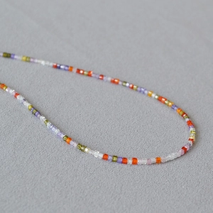 Detail view of colorful square crystal beads with jelly texture on a grey fabric
