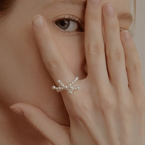 Elegante anello di perle intrecciate con un design a nodo sulla mano della modella