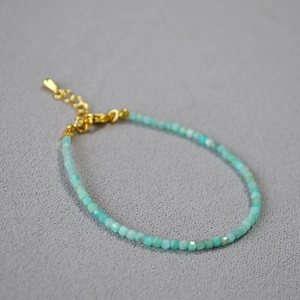 Dettaglio del bracciale con pietre azzurre sfaccettate e chiusura a moschettone dorata