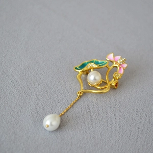Détail de la broche lotus en émail avec perle pendante sur une base en laiton doré