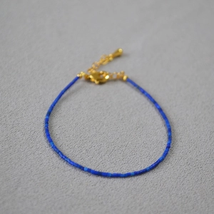 Macro detail of turquoise lapis beaded bracelet with gold lobster clasp and chain