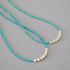 Détail d'un collier en perles de turquoise avec perles d'eau douce blanches et dorées