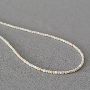Gros plan de perles carrées en apatite et nacre pastel sur un collier délicat