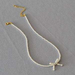 Elegant pearl choker necklace with a delicate bow pendant on grey textured fabric