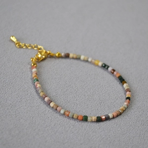 Dettaglio ravvicinato di perle in pietra naturale sfaccettate su bracciale dorato