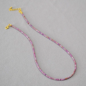 Détail du collier de perles en pierre violette avec fermoir mousqueton doré et chaînette