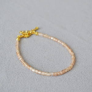 Champagne crystal square bead bracelet with adjustable gold lobster clasp on grey knit