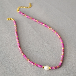 Detail of beaded necklace with fuchsia marble beads and white baroque pearl accent