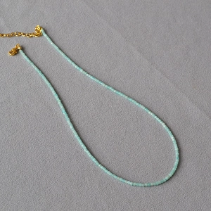 Detailansicht der mintblauen Natursteinperlen mit goldenem Karabinerverschluss und Kette