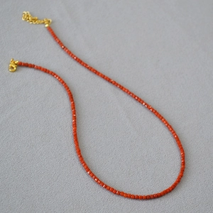 Close-up of red agate faceted beads with gold lobster clasp and adjustable metal chain