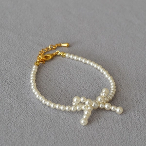 Detail of pearl bow necklace with golden lobster clasp and adjustable link chain