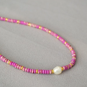 Detail of colorful beads with gold spacers and a white baroque pearl on a choker necklace