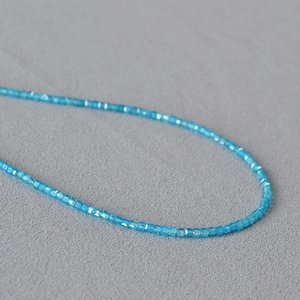 Macro detail of sky blue faceted square crystal beads on a delicate choker necklace