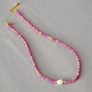 Bohemian style necklace with pink purple beads and freshwater pearl on dark fabric