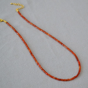 Macro detail of red faceted agate beads and golden adjustable lobster clasp on necklace