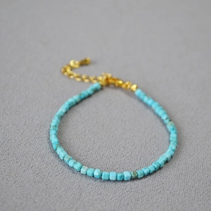 Dettaglio di perline turchesi quadrate e chiusura dorata su un bracciale di classe