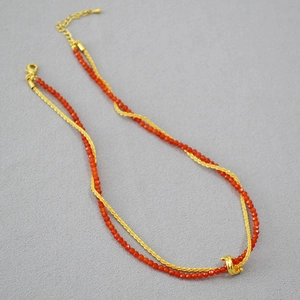 Detail of double-layer necklace with red agate beads and golden twisted knot link