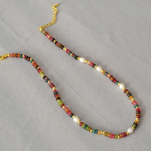 Detail of colorful beads and white freshwater pearls with gold lobster clasp and chain