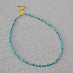 Gros plan d'un collier de perles d'apatite bleue avec fermoir mousqueton doré réglable