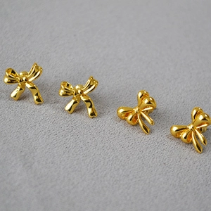 Macro shot of gold-plated brass bow earrings showing polished texture and elegant design
