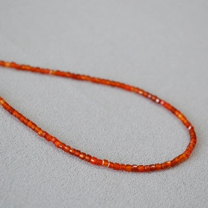 Macro shot of faceted orange-red carnelian beads on a minimalist strand necklace