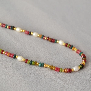 Close-up of colorful gemstone beads and freshwater pearls on a gold-plated link necklace