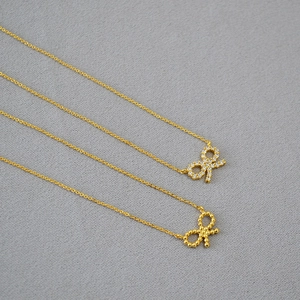 Détail de pendentifs nœud avec pavé de zircons et textures perlées dorées élégantes
