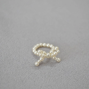 Dettaglio di un elegante anello a fiocco di perle con perline intrecciate su maglia