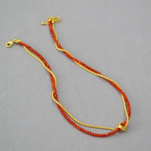 Double-layer necklace with red carnelian beads and gold metal chain featuring a knot design