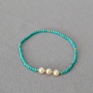 Détail macro de perles turquoise avec perles d'eau douce et séparateurs dorés sur tissu