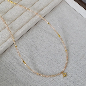 Détail du collier à perles avec zircons champagne et pendentif étoile octogonale