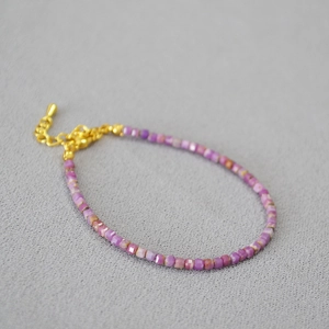 Détail du collier de perles en pierres violettes avec fermoir et chaîne dorés polis