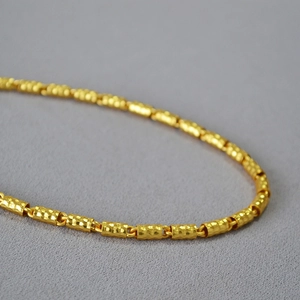 Primo piano della collana a catena in oro a bambù con texture in metallo martellato