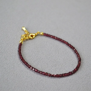Bracciale minimalista con perline di granato bordeaux e chiusura a moschettone dorata regolabile