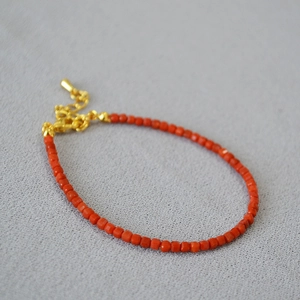 Macro shot of red faceted agate beads with gold adjustable lobster clasp and chain