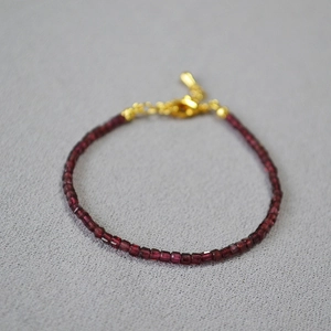 Dettaglio del bracciale con perle di granato rosso sfaccettato e chiusura dorata regolabile